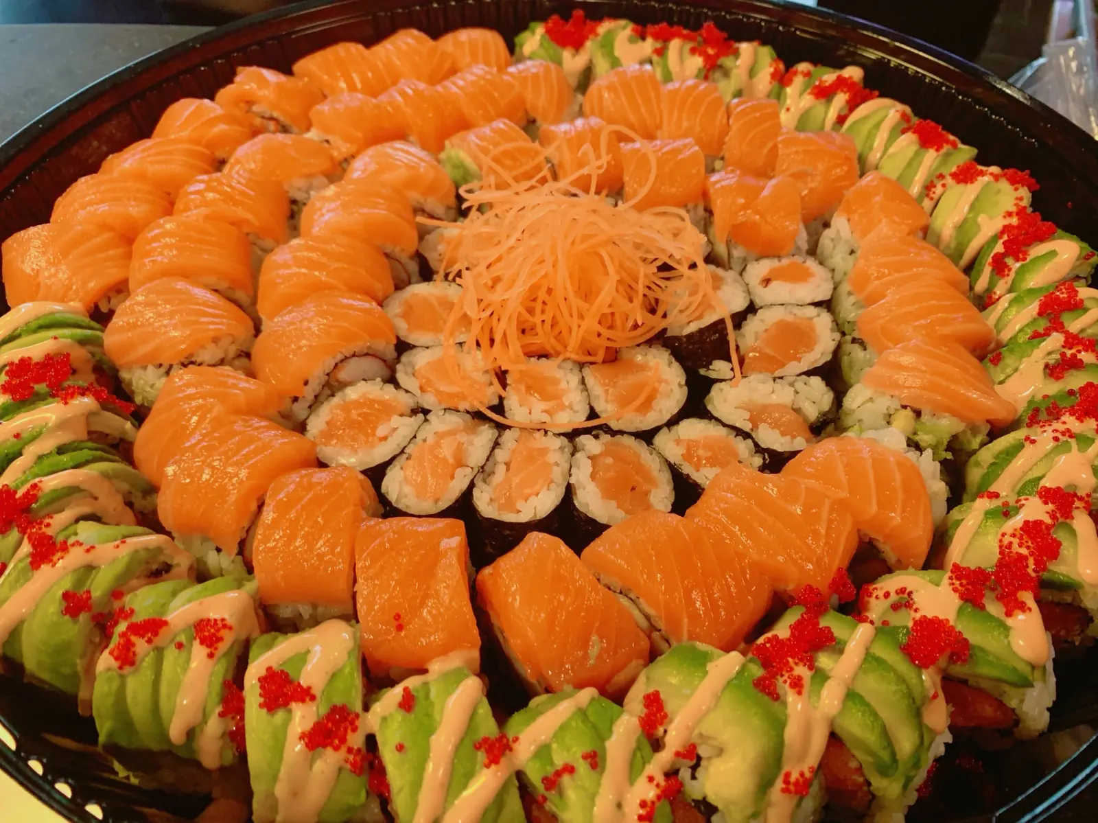 A party tray of salmon-topped rolls and salmon maki